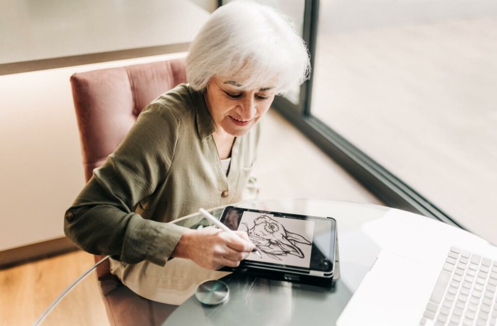 An older adult woman using her ipad to create digital art.