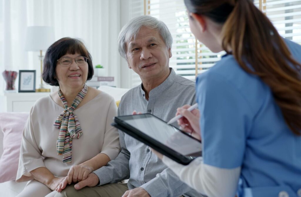 A caregiver discussing a personalized care plan with an older adult couple in assisted living.