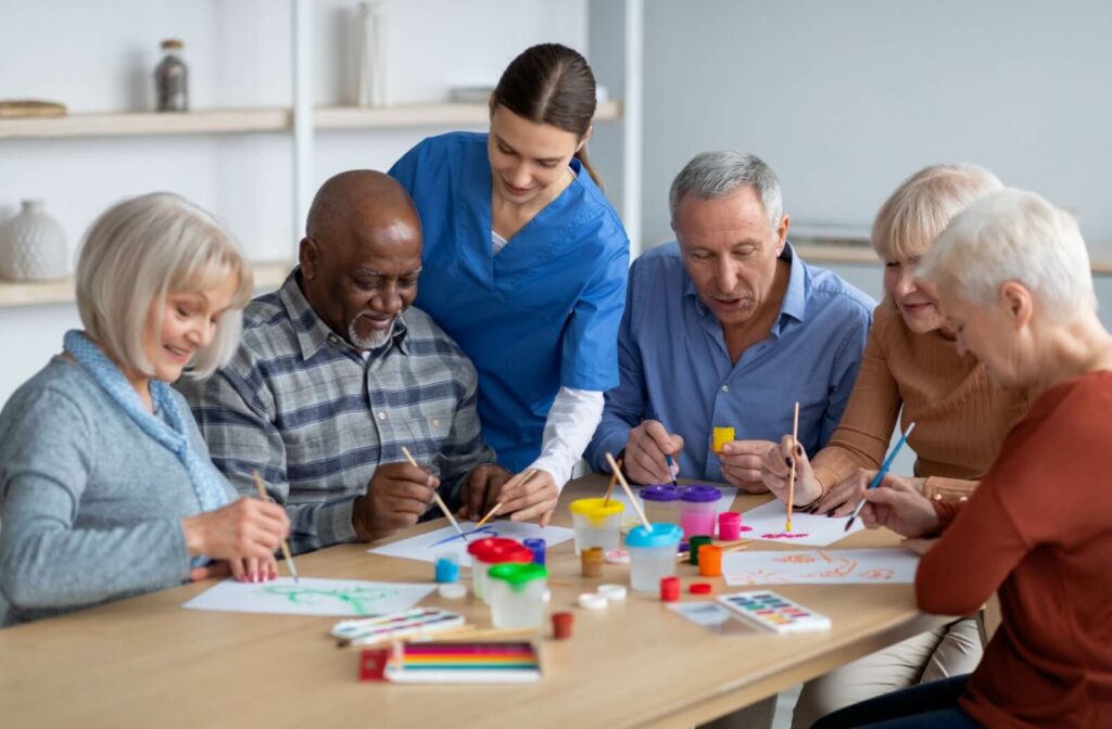 A group of older adults engaging in a painting activity with an instructor's assistance.
