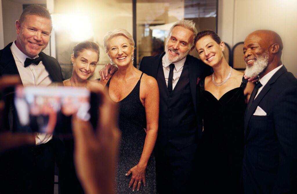 A group of well-dressed older adults gather at a social event for a photo.